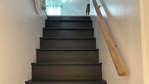 Un escalier avec une main courante en bois et une rampe noire.