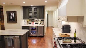 A modern kitchen with a central island, stainless steel appliances, and a wooden floor. - Walking Distance to Square and Campus, Spacious 5-Bedroom House (Oxford)