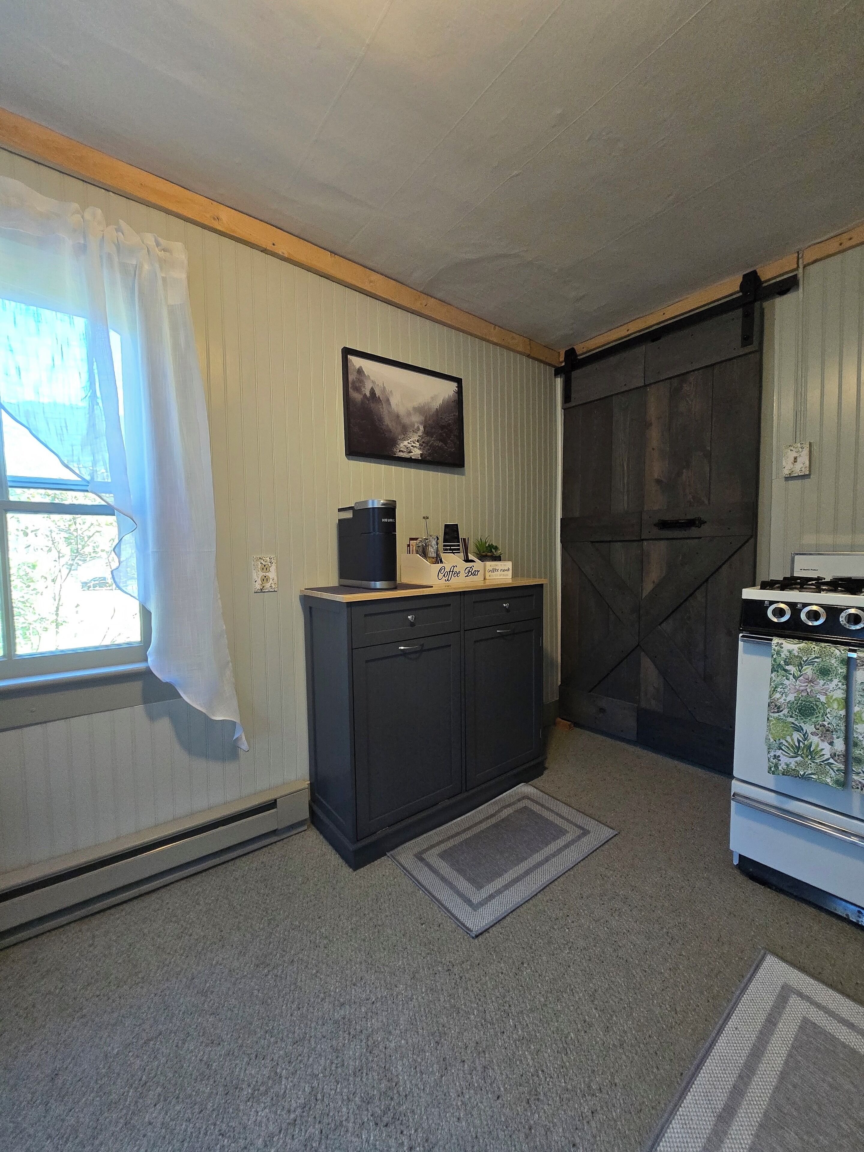A kitchen with a coffee maker, a stove, and a cabinet.