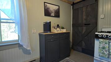 A kitchen with a coffee maker, a stove, and a cabinet.