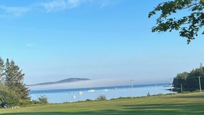 A golf course with a view of the ocean and a distant mountain. - Peaceful Green Lake Get-A-Way (Ellsworth)