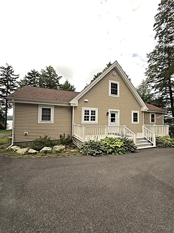 A two-story house with a front porch, a small front yard with rocks and plants, and a driveway. - Peaceful Green Lake Get-A-Way (Ellsworth)