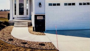 Una casa de dos pisos con garaje, porche delantero y entrada para vehículos.
