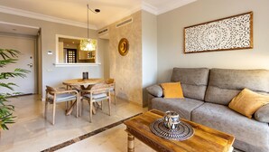 A living room with a grey sofa, a wooden coffee table, and a dining area with a wooden table and chairs.
