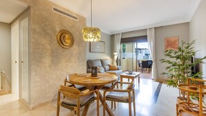 A dining area with a round wooden table, wicker chairs, and a hanging light fixture.
