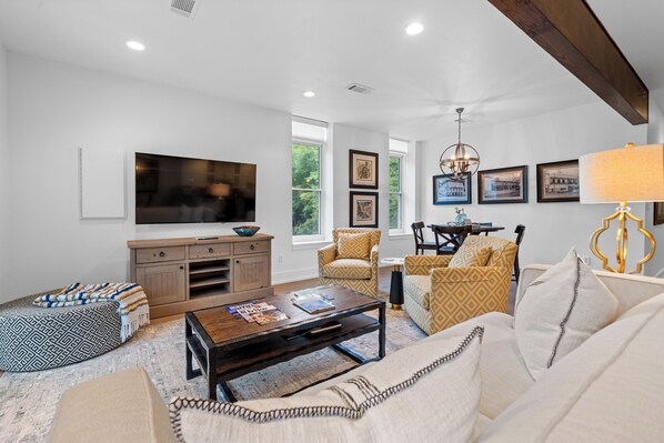 A spacious living room with a large flat-screen TV, comfortable seating, and a coffee table.