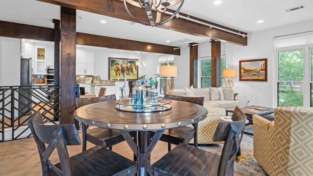 Amplia sala de estar con una mesa redonda de madera, sillas de madera oscura, un sofá y un sillón estampado.