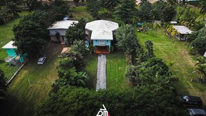 An aerial view of a property with a central building, a driveway, and a beach in the background.