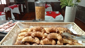 Un buffet de petit-déjeuner avec des croissants et d’autres viennoiseries, un distributeur de sucre et une plante en pot.