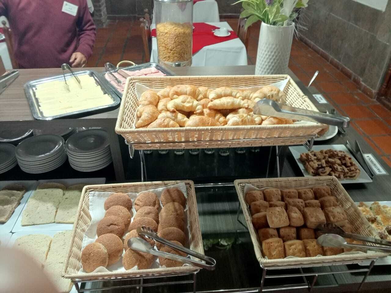 Un buffet proposant une variété d’aliments, notamment du pain, des viennoiseries et des biscuits.