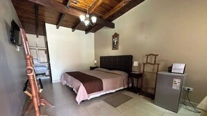 Une chambre à coucher avec un lit, une commode, un téléviseur et un ventilateur de plafond.