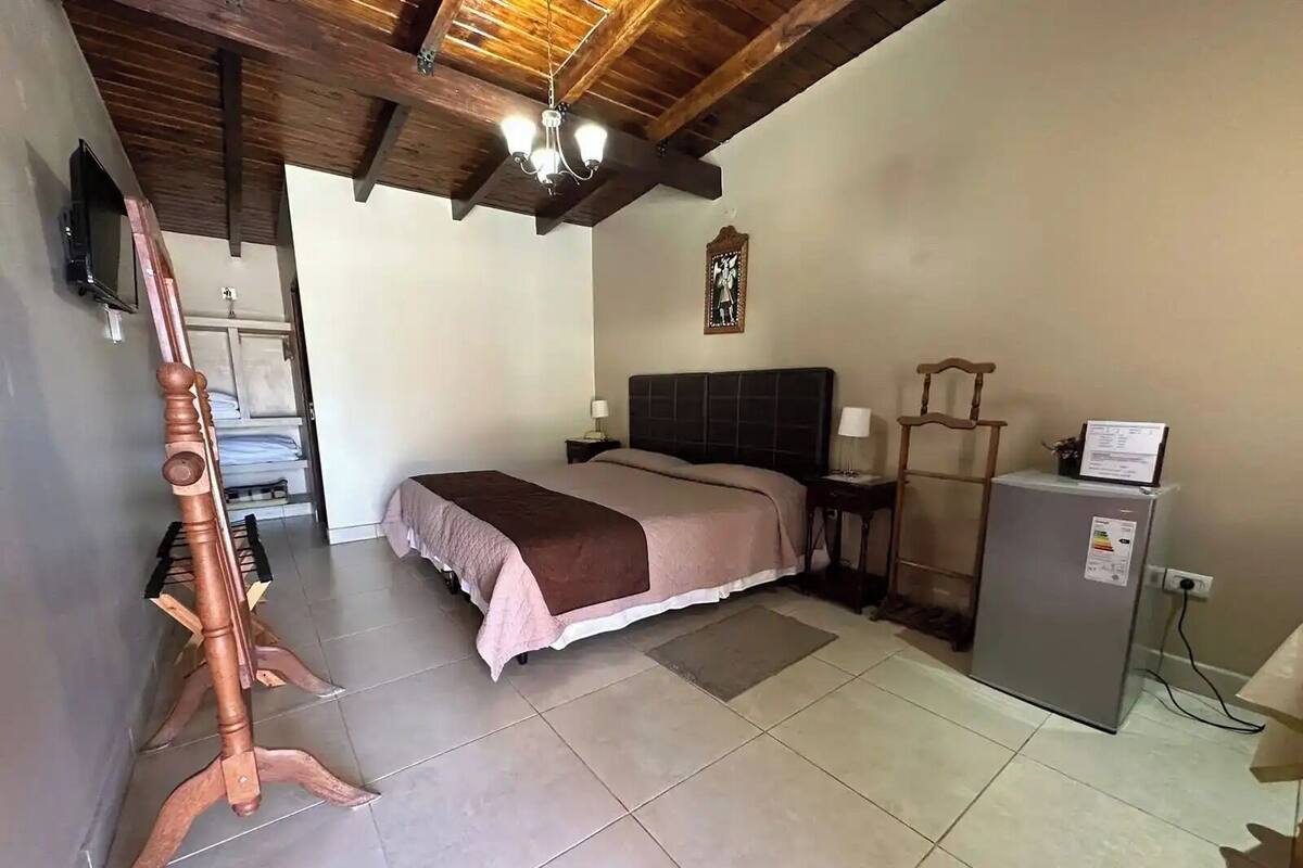Een slaapkamer met een bed, een dressoir, een televisie en een plafondventilator.
