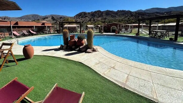Une piscine entourée d’une pelouse verdoyante, de chaises longues et avec une chaîne de montagnes en toile de fond.