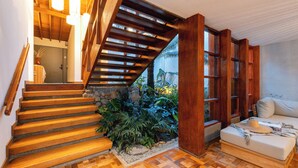 A staircase with wooden steps leading to a room with a bed, a small indoor garden, and a view of the outdoors.