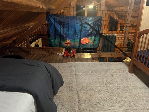 A bedroom with a view of a wooden staircase leading to a loft area. - Charming 3-bedroom cabin in Eucha with WiFi and FirePit (Eucha)