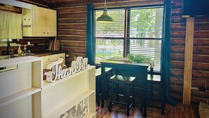 A rustic cabin interior with a wooden interior, a kitchen area, and a dining table with chairs. - Charming 3-bedroom cabin in Eucha with WiFi and FirePit (Eucha)