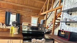 A kitchen with a stainless steel stove, oven, and microwave. There are wooden cabinets and a wooden ceiling. - Charming 3-bedroom cabin in Eucha with WiFi and FirePit (Eucha)