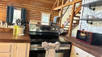 A kitchen with a stainless steel stove, oven, and microwave. There are wooden cabinets and a wooden ceiling.