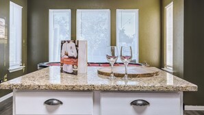 A kitchen with granite countertops, white cabinetry, and a window with blinds. - 5BR Retreat: Arcade, Cowboy Pool & Volleyball Oasis in Huge Backyard (Round Rock)