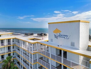 Un hotel frente a la playa con varios balcones, vista al mar y el logotipo de Smyrna Beach Club.