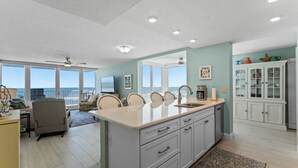 A spacious kitchen with a large island, white cabinetry, and a view to the outside.