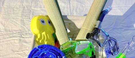 A tray with a yellow rubber duck, rolled blue towels, a beaded necklace, and a pair of scissors.