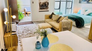 A modern living room with a sofa, coffee table, and decorative items. There is a large window with a view of the outdoors.
