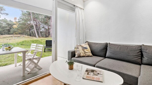 Un salon moderne avec un canapé gris, une table basse ronde et un coin repas comprenant une table et des chaises blanches.