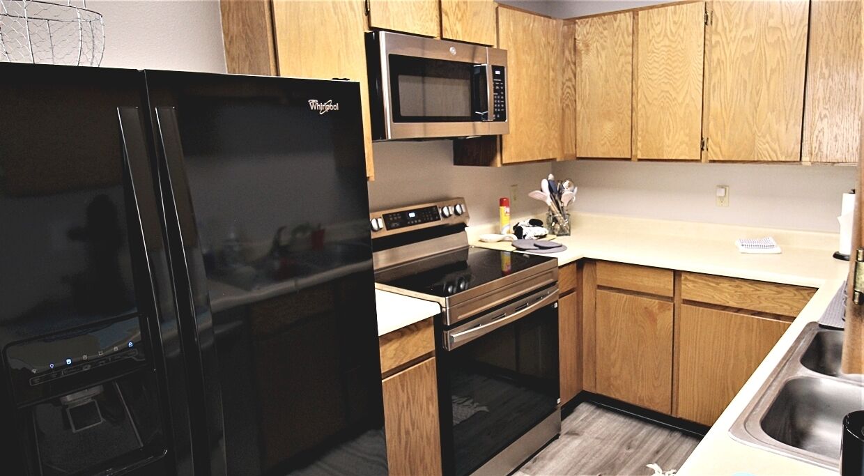 A kitchen with a refrigerator, microwave, oven, and sink.