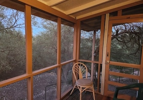 Un espacio al aire libre techado con una silla de madera y una puerta.