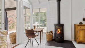 Una stanza accogliente con un camino in legno nero, un tavolo di legno con sedie e un cesto in vimini.