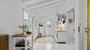 Una cucina con mobili bianchi, un piano di lavoro in legno e un appendi pentole a sospensione.