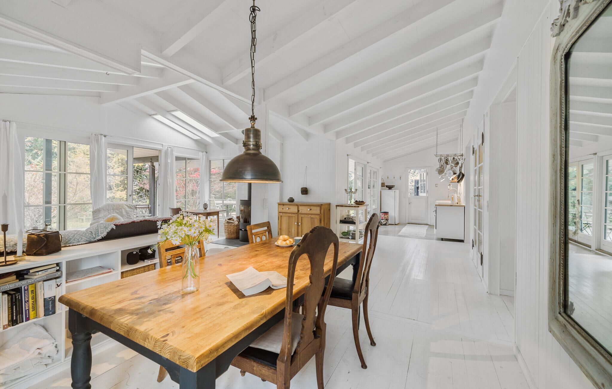 A spacious kitchen with a wooden table, chairs, and a hanging light fixture.