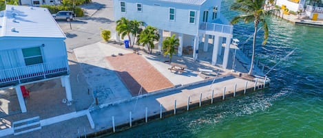 A waterfront property with a dock, a covered patio, and a pool area.