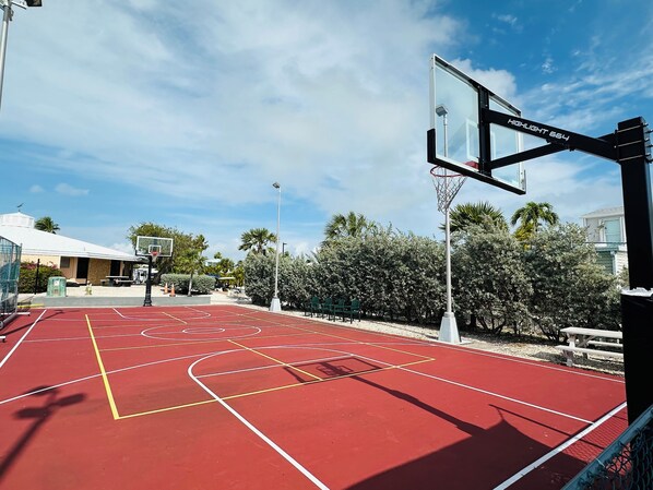 An outdoor basketball court with a red surface, a basketball hoop, and a clear sky. - 219 Oceanfront RV Lot 59' Seawall (Cudjoe Key)