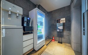 Una habitación de hotel moderna con minibar, refrigerador, máquina expendedora y extintor.