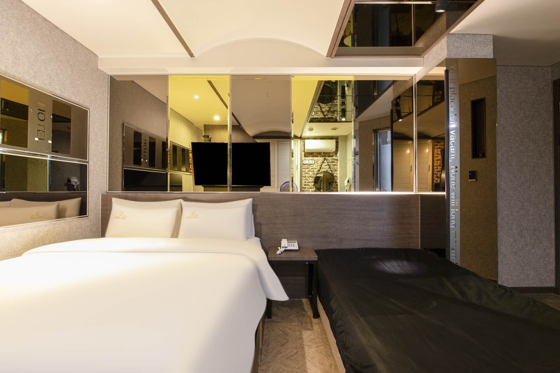 Quarto de hotel moderno com uma cama grande, mesa de cabeceira, TV de tela plana e espelho.