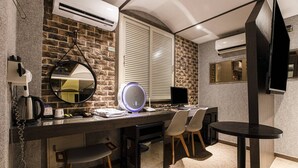 A modern kitchen with a brick wall, a round mirror, a built-in oven, and a small dining area with a round table and chairs. - Hotel Louize (Seoul)