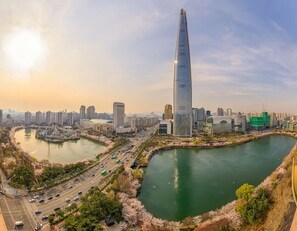 A modern skyscraper with a sleek, tapering design, surrounded by a river and a mix of high-rise and mid-rise buildings. - Hotel Louize (Seoul)
