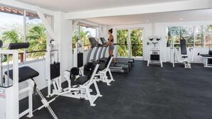A gym with treadmills, weight machines, and a large window offering a view of palm trees.