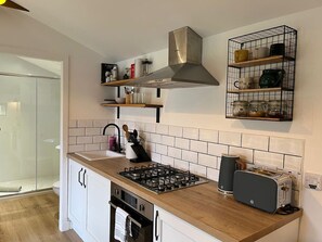 Een koelkast, een oven, een broodrooster, kookgerei, borden en bestek