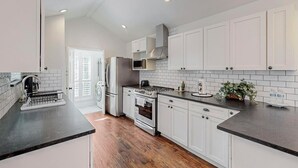 A modern kitchen with white cabinets, a black countertop, and stainless steel appliances.
