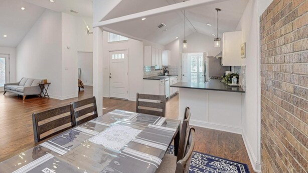 A spacious kitchen with white cabinets, a central island, and a dining area with a large table and chairs.