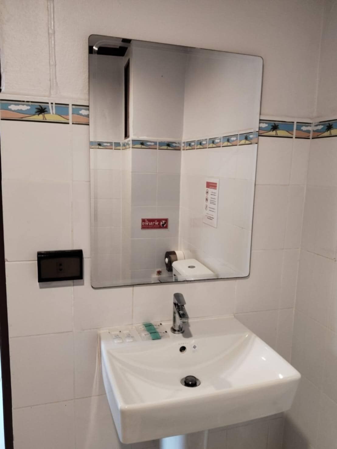 A bathroom with a white sink, a mirror, and a hand dryer.