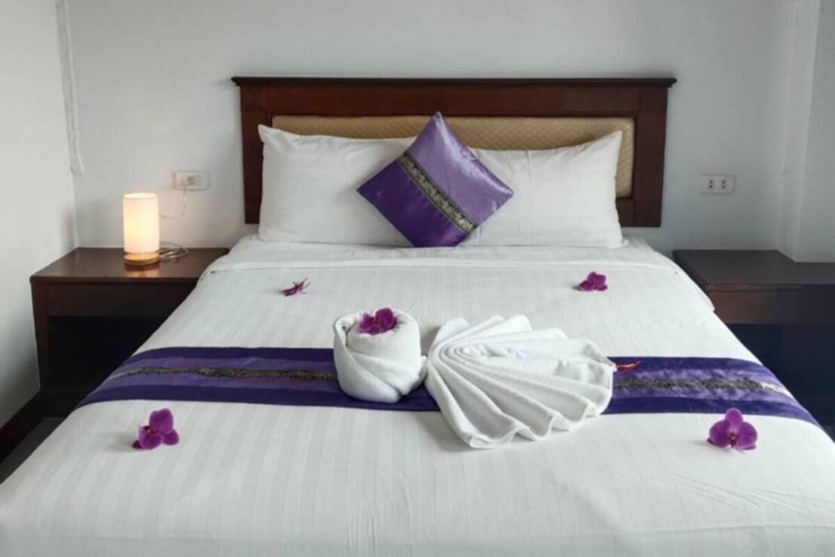 Une chambre d’hôtel avec un lit, une table de chevet avec une lampe et un appareil de climatisation fixé au mur.