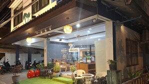A hotel entrance with a welcoming sign, outdoor seating area, and potted plants. - Samui Grand mansion (Koh Samui)
