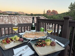 A table with a fish, vegetables, and drinks, set on a balcony with a scenic view. - Sedona Cathedral Magic, Walk to Oak Creek, Unmatched Red Rock Views, Private Decks (Sedona)