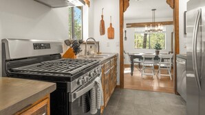 A modern kitchen with a stainless steel stove, wooden cabinets, and a large island. - Delightful 3-bedroom house in charming Flagstaff w/King Size Bed & Gas Log Stove (Flagstaff)