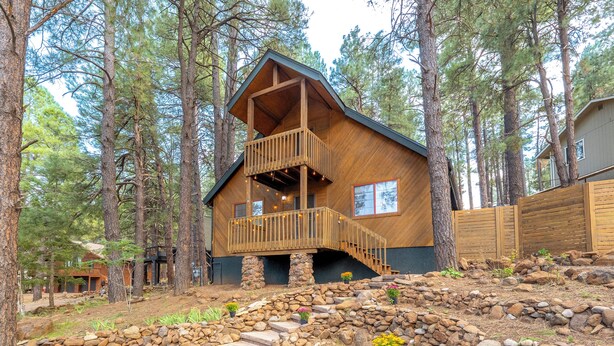 A wooden cabin with a balcony, surrounded by trees and a stone pathway. - Delightful 3-bedroom house in charming Flagstaff w/King Size Bed & Gas Log Stove (Flagstaff)