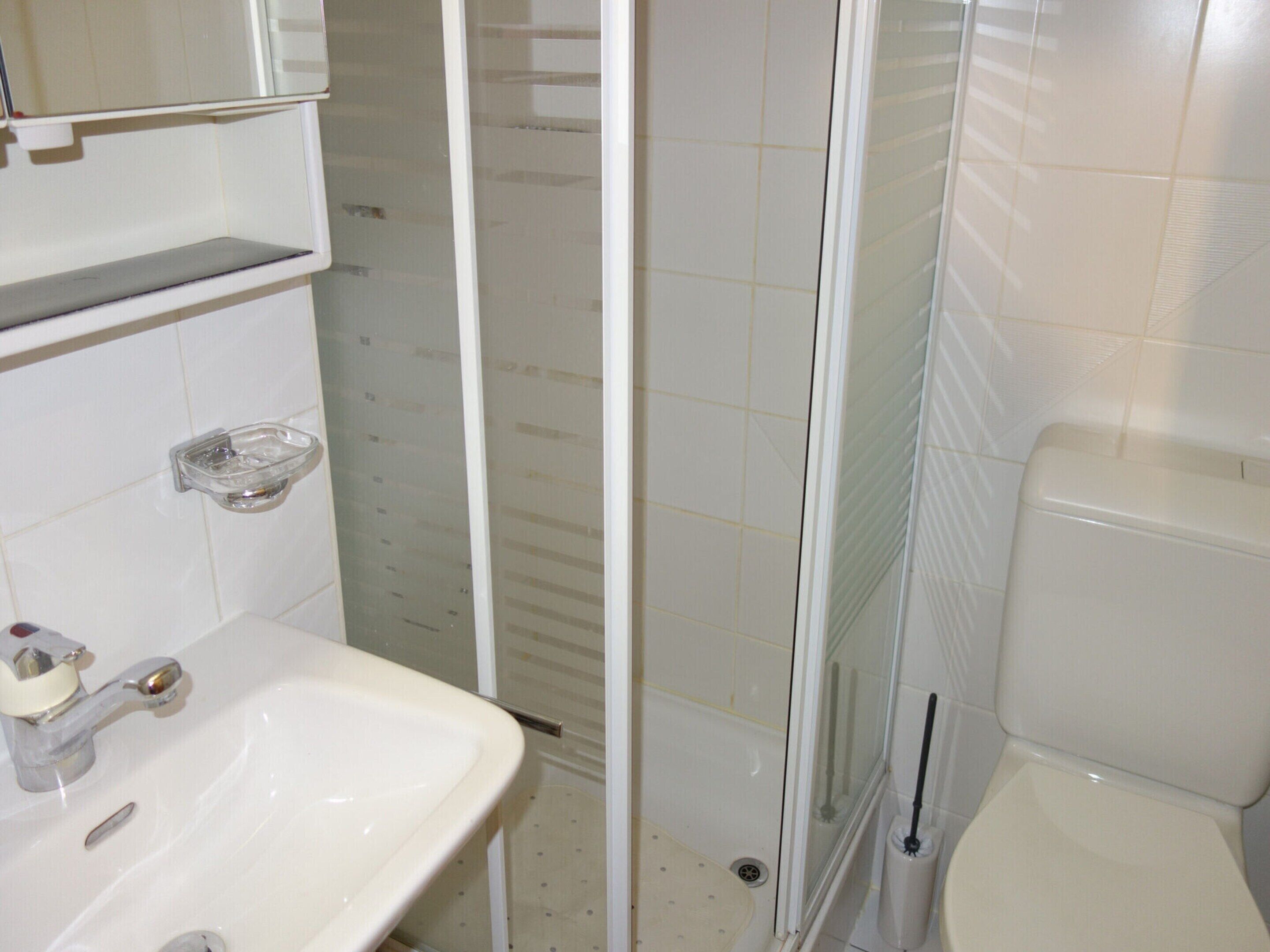 A bathroom with a sink, toilet, and glass shower enclosure.
